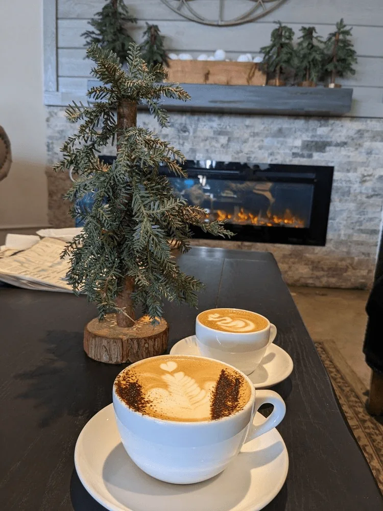 Lattes beside a small tree and the fireplace