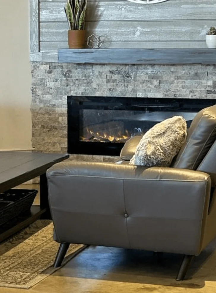 Leather couch in front of the stone fireplace