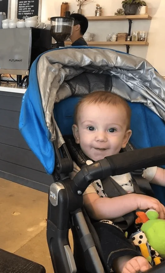 A baby smiling in a stroller