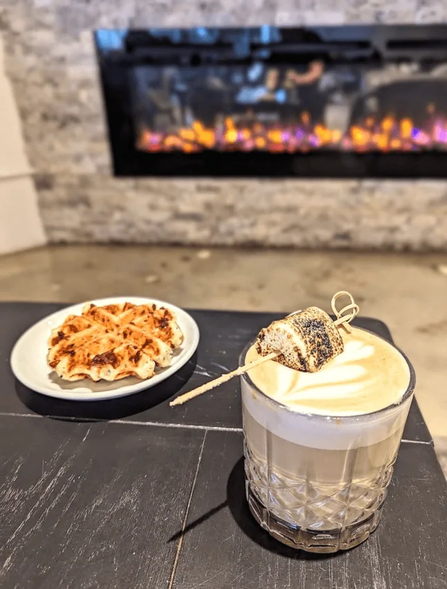 A waffle and a latte by the fireplace