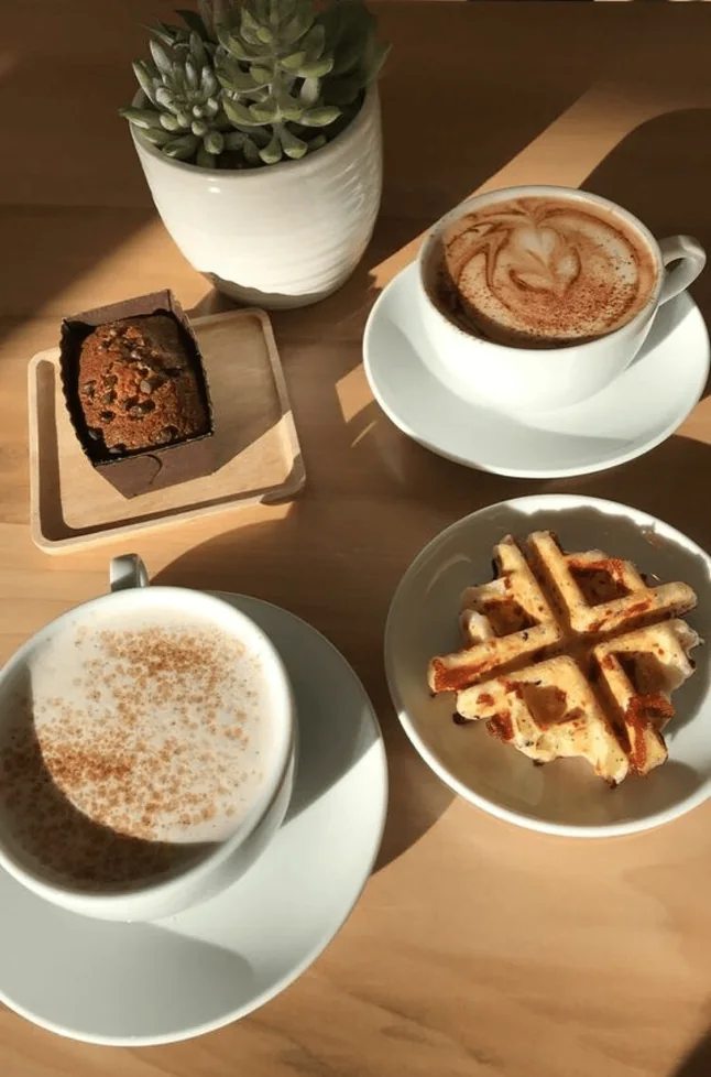 Cappuccino, coffee and a waffle on a table